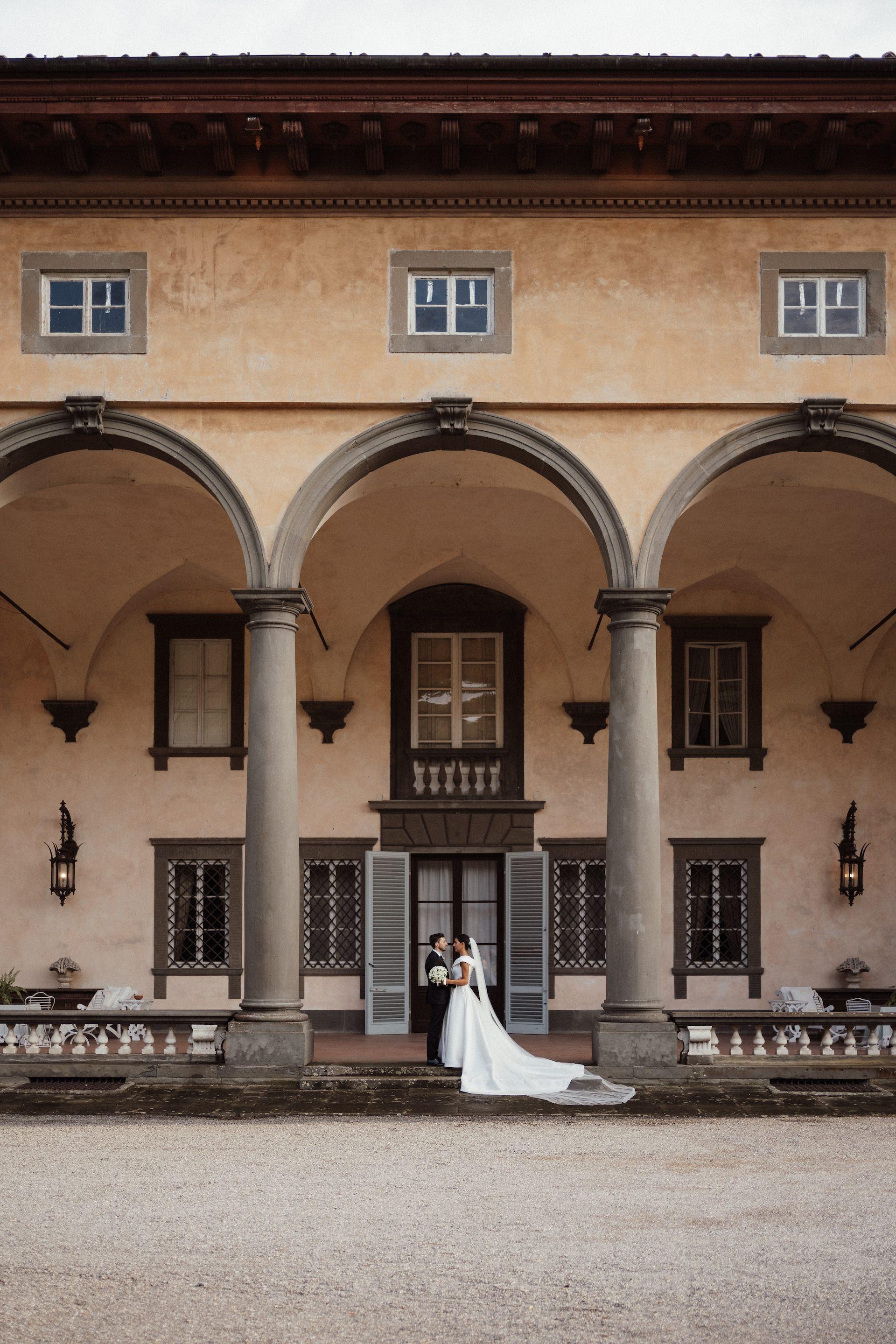 Long shot of a couple of newlyweds under the entrance portico of a villa.